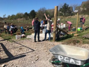two people by a gate with a silver wheelbarrow in the foreground
