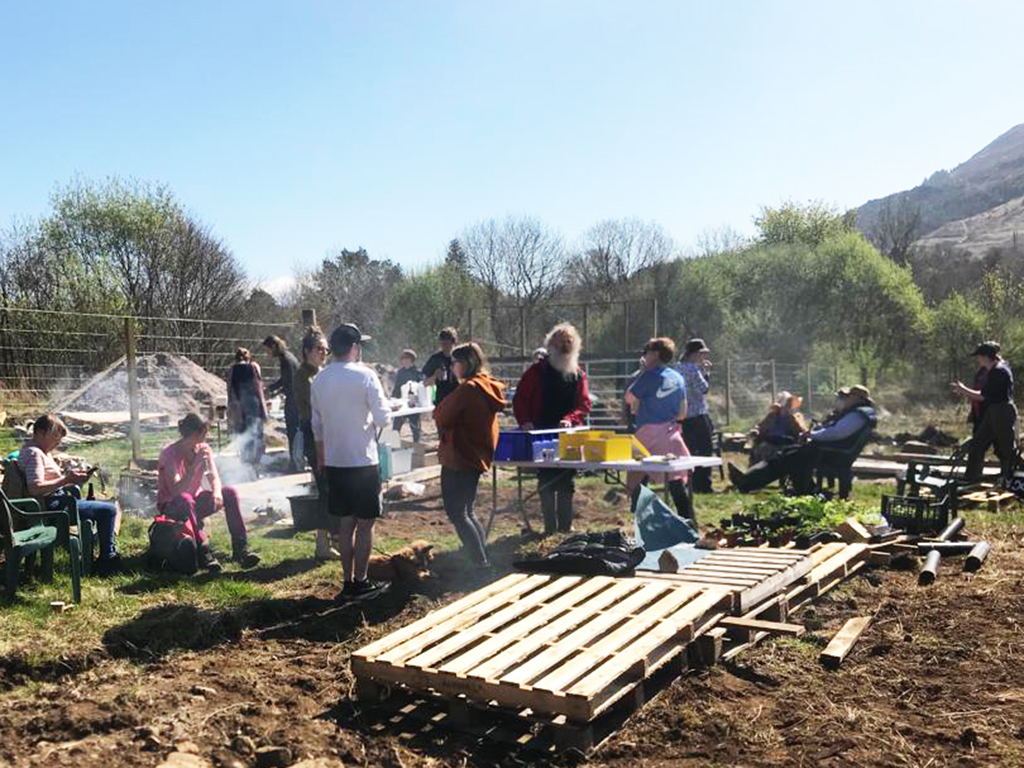 people gather on a brown filed with hills in distance and a pallet in the foreground