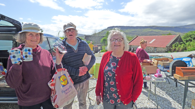 Three seniors holding items purchased at the event