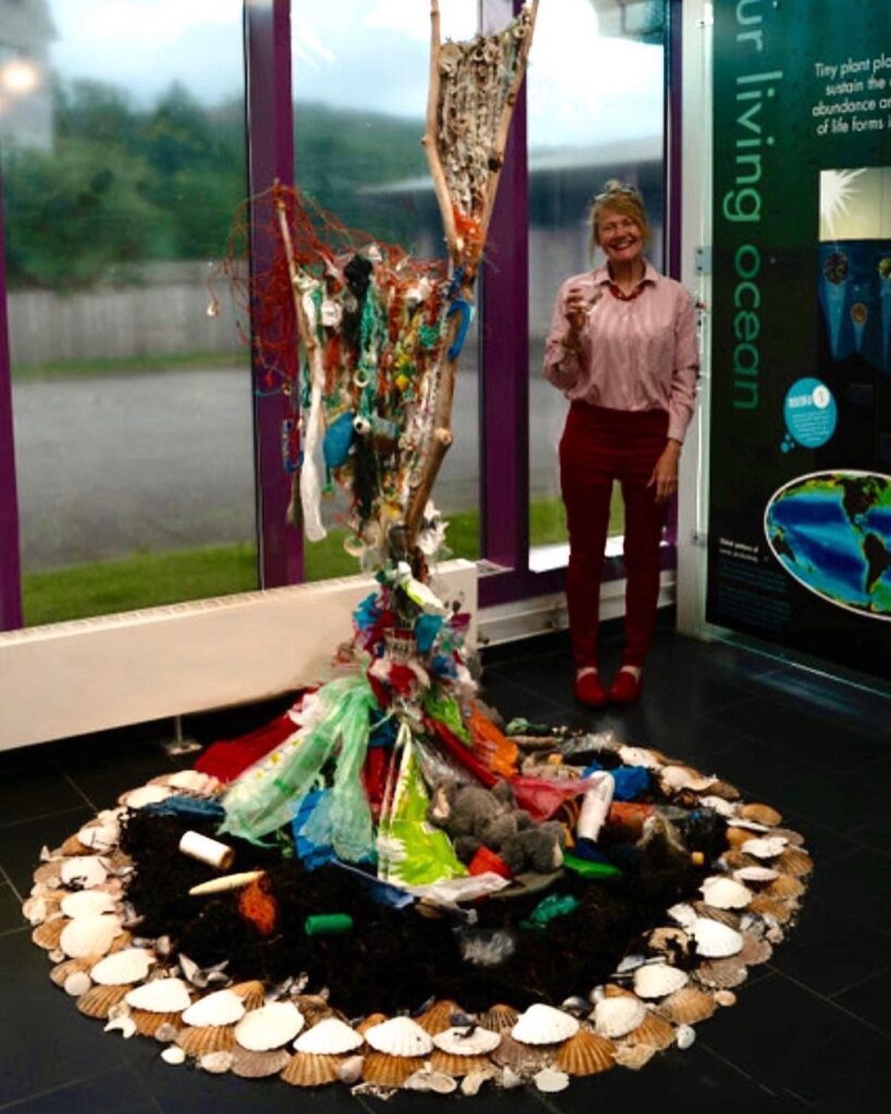 plastic debris suspended in a ring of snd a shells, the artist stands nearby
